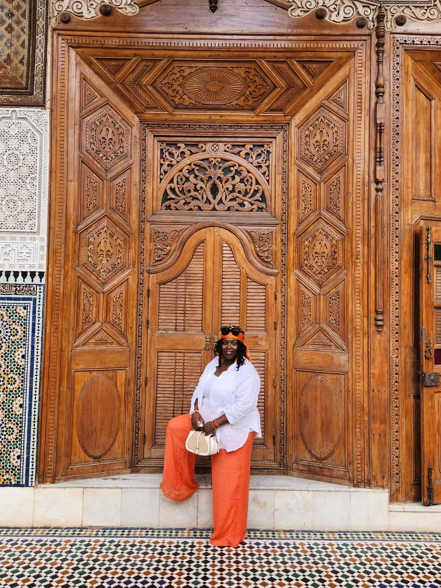 Merley sits on the step of a large carved wooden doorway.
