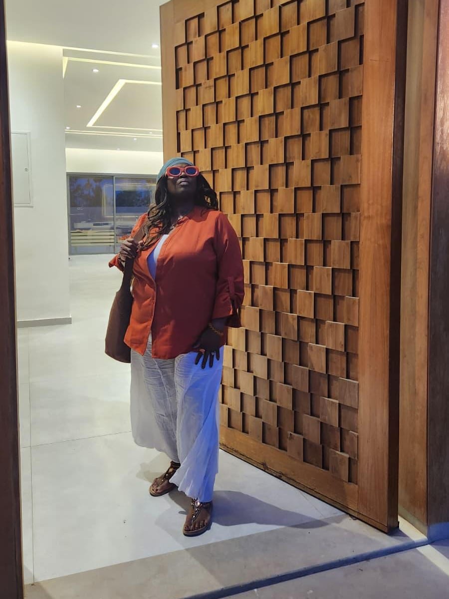 Merley beside a tall wooden door carved in raised squares.